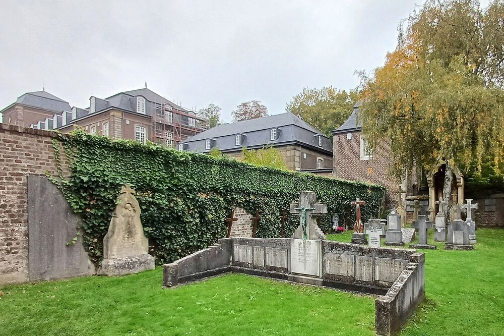 Gebouwen van abdij Rolduc in Kerkrade gezien over de kloosterbegraafplaats, met herfstbomen